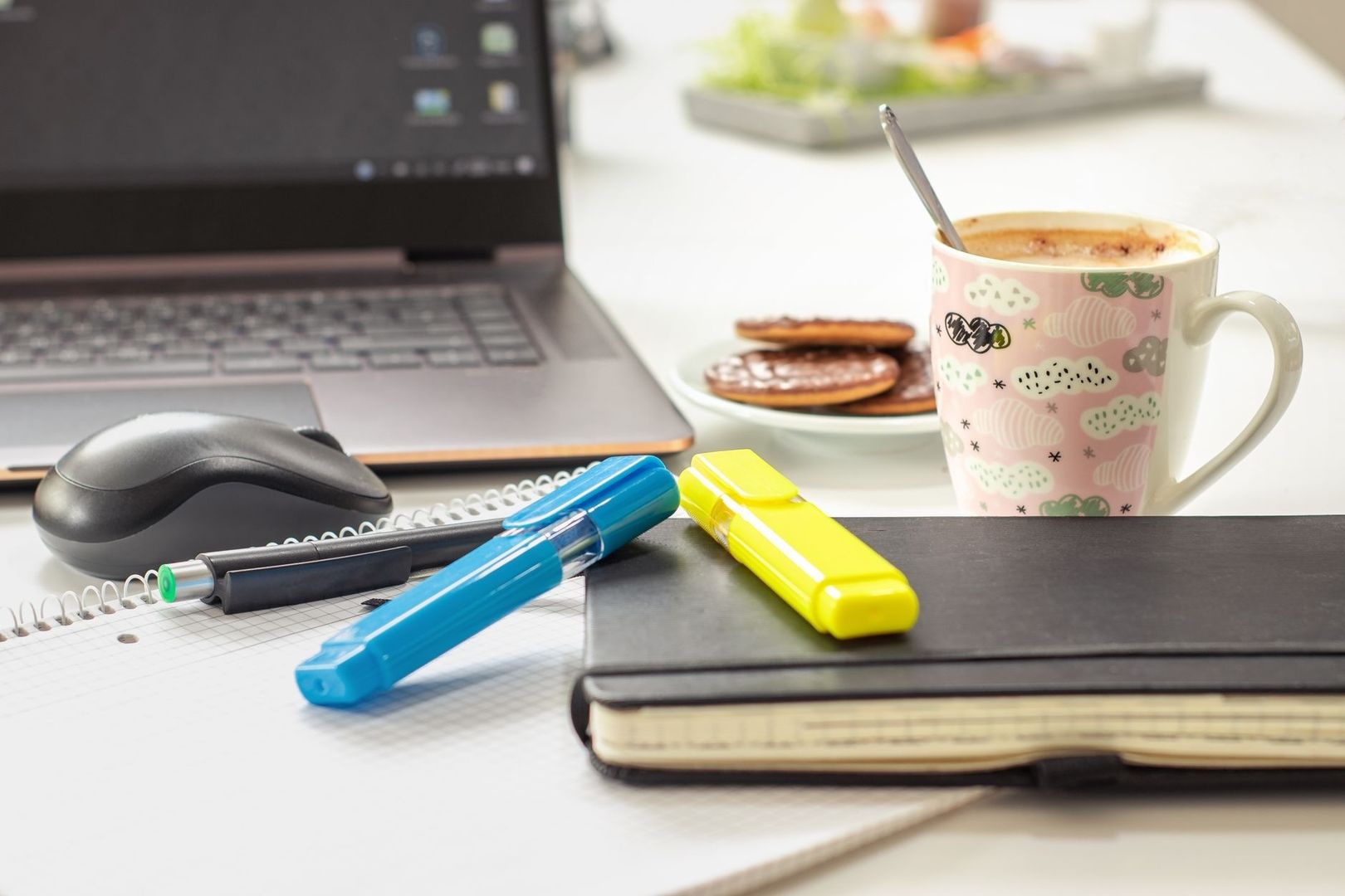 Lekfullt hemmakontor med laptop, färgglada pennor, kaffe och kakor